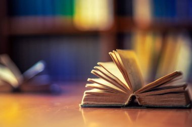 Kütüphanedeki masanın üzerinde açık bir kitap yatıyor.
