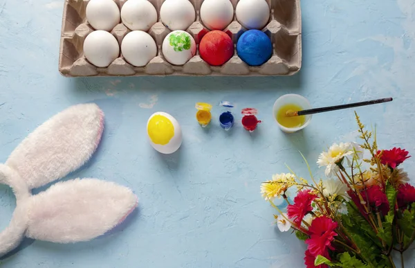 Пасха, краска и окрашенные яйца, цветы, яркие и белые кроличьи уши — стоковое фото