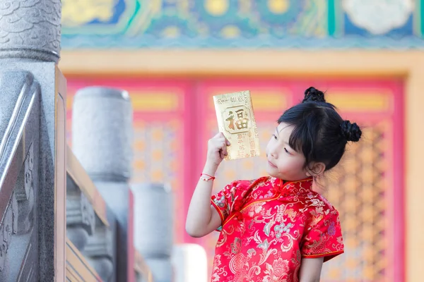 Adorable happy Chinese girl showing golden envelope that contain