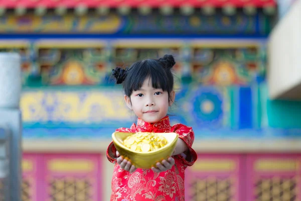 Adorable happy Chinese girl receiving gold bar on Chinese New Ye