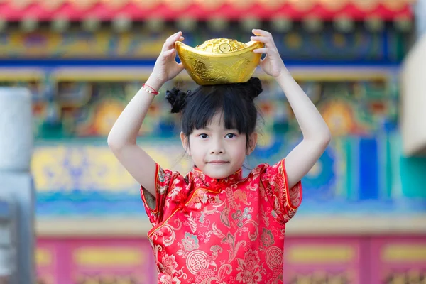 Adorable happy Chinese girl receiving gold bar on Chinese New Ye