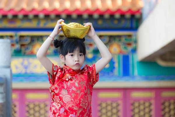 Adorable happy Chinese girl receiving gold bar on Chinese New Ye