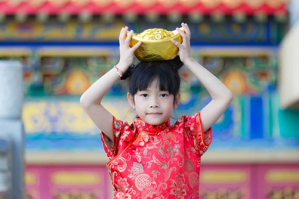 Adorable happy Chinese girl receiving gold bar on Chinese New Ye