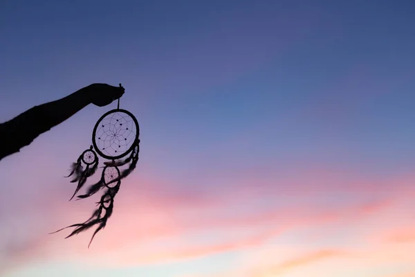 Silhuetten av Dream Catchers hålla upp i luften under solnedgången pe Royaltyfria Stockfoton