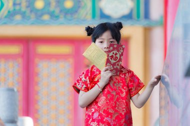 Sevimli Çinli kız, içinde Çince kelime olan Xinfu 'nun bulunduğu altın ve kırmızı zarfları açıyor. Çin' in yeni yılı için mutluluk anlamına geliyor.