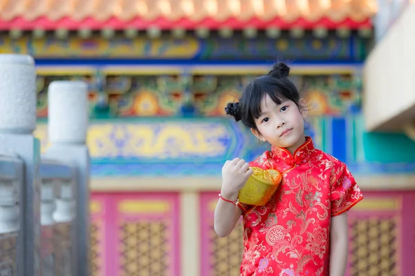 Adorable happy Chinese girl receiving gold bar on Chinese New Year