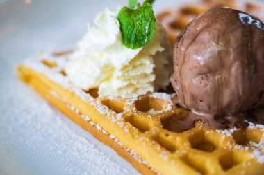 Çikolatalı dondurma, yumuşak krema, beyaz tabakta peynirli waffle.
