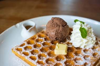 Çikolatalı dondurma, yumuşak krema, beyaz tabakta peynirli waffle.