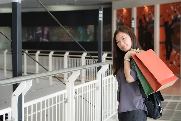 Portrait of happy Asian girls shopping with colored bags.