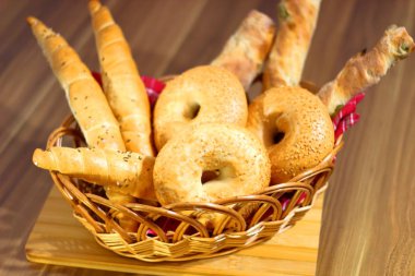 Ekmek hamuru, simit ve rulo, sepetin içinde, masada duran tahta bir tahtanın üzerinde kırmızı bir peçete..