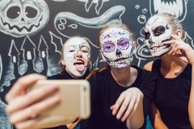 Üç kız Halloween gidiyor, grimace desen ile selfie karanlık bir arka plan yapmak