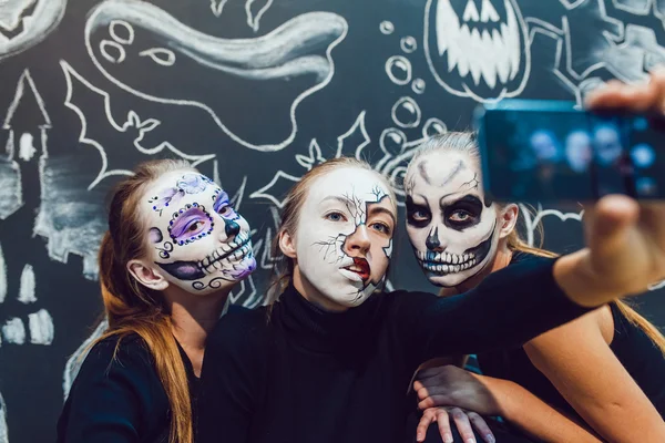 Три девушки собираются на Хэллоуин, гримаса сделать селфи темный фон с шаблоном — стоковое фото
