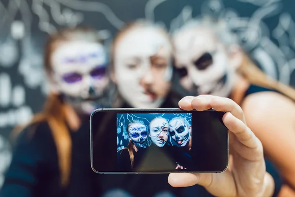 Three girls going on Halloween, grimace make selfie  a dark background with  pattern — Stock Photo, Image