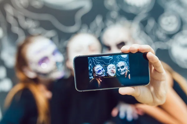 Three girls going on Halloween, grimace make selfie  a dark background with  pattern — Stock Photo, Image