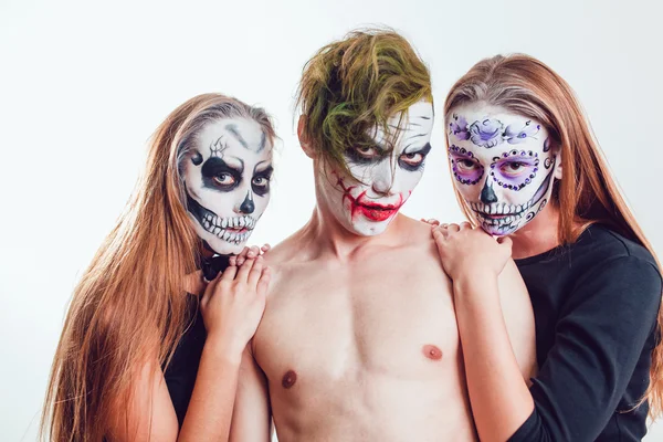 Две девушки и парень с хэллоуинским лицом на белом фоне — стоковое фото