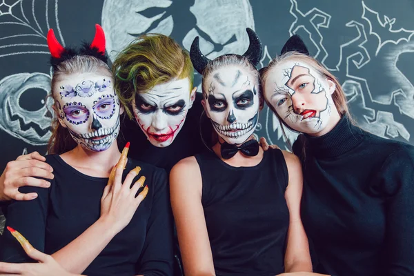 Три девушки и парень с рисунком лица Хэллоуина на темном фоне — стоковое фото