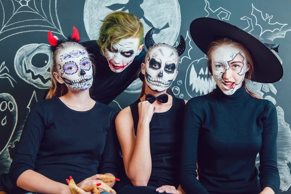 Drie meisjes en een man met Halloween gezicht kunst op donkere achtergrond patroon — Stockfoto