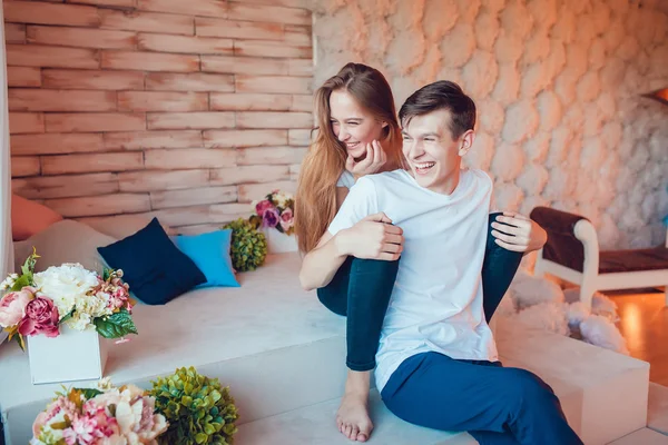 Молодая пара сидит обнимаясь и веселясь дома — стоковое фото