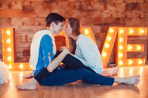 Jong koppel om thuis te zitten op de verdieping tegenover elkaar hand in hand — Stockfoto