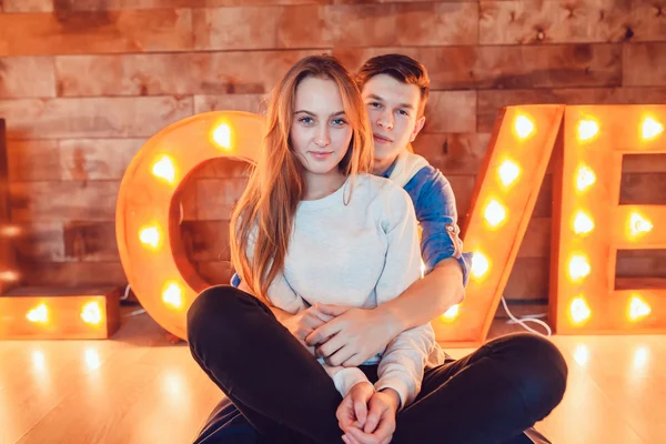 Ungt par i kärlek sitter på golvet embracing — Stockfoto