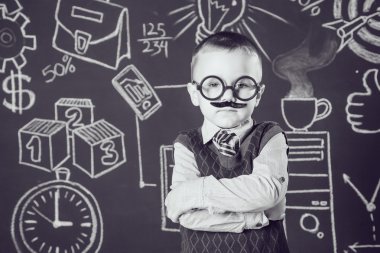 Bıyıklı ve gözlüklü işadamı ya da öğretmen olarak küçük çocuk ellerini koyu bir arka plan deseni üzerine katlanmış duruyor