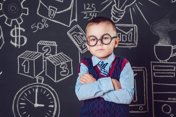 Niño pequeño como hombre de negocios o maestro con gafas de pie sus manos dobladas sobre un patrón de fondo oscuro —  Fotos de Stock