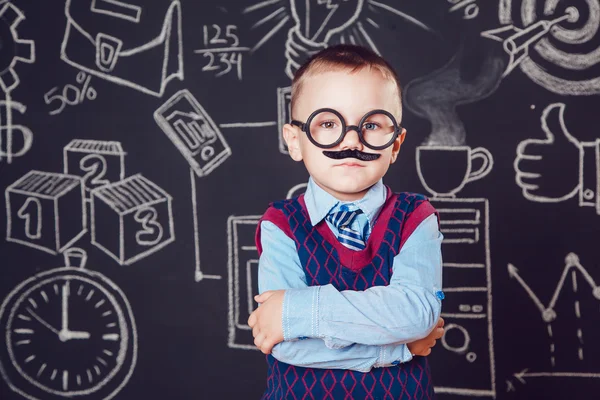 Mały chłopiec jako biznesmen lub nauczyciel z wąsy i okulary stojący jej ręce składane na ciemnym tle wzór — Zdjęcie stockowe