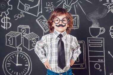 Bıyıklı ve gözlüklü bir öğretmen olarak küçük çocuk karanlık bir arka plan deseni üzerinde duruyor. Gömlek, kravat giyme