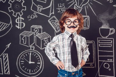 Bıyıklı ve gözlüklü bir öğretmen olarak küçük çocuk karanlık bir arka plan deseni üzerinde duruyor. Gömlek, kravat giyme