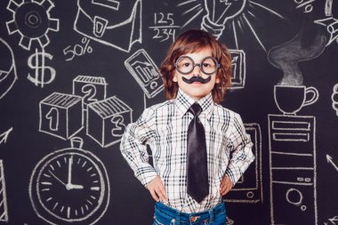 Bıyıklı ve gözlüklü bir öğretmen olarak küçük çocuk karanlık bir arka plan deseni üzerinde duruyor. Gömlek, kravat giyme