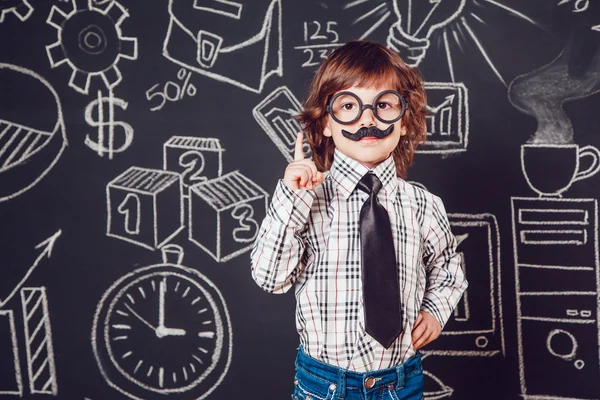 Μικρό αγόρι ως επιχειρηματίας ή δάσκαλο με μουστάκι και γυαλιά που στέκεται πάνω σε σκοτεινό φόντο μοτίβο. Φορώντας πουκάμισο, γραβάτα. Άρση ένα δάχτυλο — Φωτογραφία Αρχείου