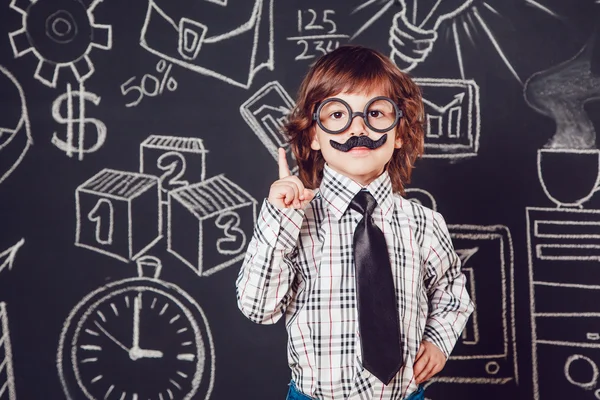 Μικρό αγόρι ως επιχειρηματίας ή δάσκαλο με μουστάκι και γυαλιά που στέκεται πάνω σε σκοτεινό φόντο μοτίβο. Φορώντας πουκάμισο, γραβάτα. Άρση ένα δάχτυλο — Φωτογραφία Αρχείου