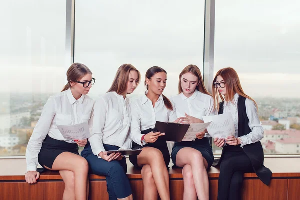 Vijf zakelijke vrouwen zitten op de vensterbank praten en bestuderen van documenten — Stockfoto