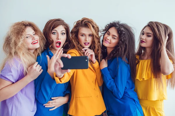 Modemädchen in heller Kleidung machen Selfie. schöne Frauen mit professionellem Make-up und verrückter Frisur, vor weißem Hintergrund. — Stockfoto