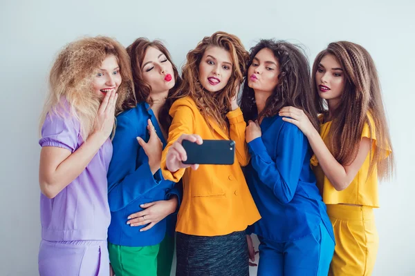 Modemädchen in heller Kleidung machen Selfie. schöne Frauen mit professionellem Make-up und verrückter Frisur, vor weißem Hintergrund. — Stockfoto