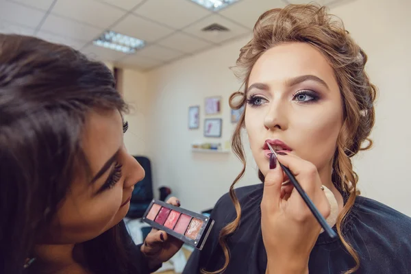 Maquillaje artista haciendo maquillaje profesional de mujer joven en estudio de belleza — Foto de Stock