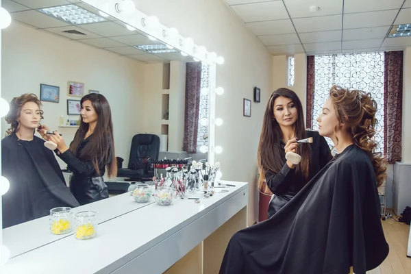 Макіяж художник робить професійний макіяж молодої жінки біля дзеркала в студії краси — стокове фото