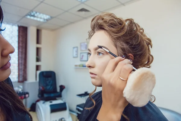 Kunstenaar doen professionele make-up van jonge vrouw in schoonheid studio make-up — Stockfoto