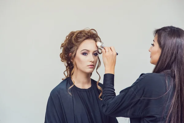 Maquillaje artista haciendo maquillaje profesional de mujer joven en estudio de belleza — Foto de Stock