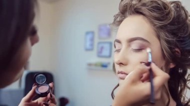 Genç kadının profesyonel göz makyajı yaparken sanatçı olun