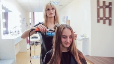 Profesyonel saç maşası güzellik Studio'yu kullanarak genç kadının saç stilisti yapar