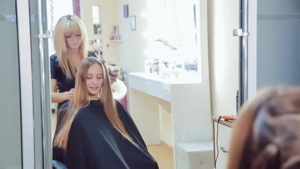 Stylista włosów sprawia, że profesjonalne fryzury młodej kobiety w studio urody — Wideo stockowe