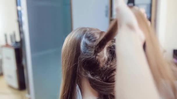 Стилист делает профессиональную прическу молодой женщины в студии красоты — стоковое видео