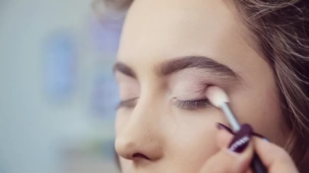 Maquillaje artista haciendo maquillaje de ojos profesional de mujer joven — Vídeo de stock