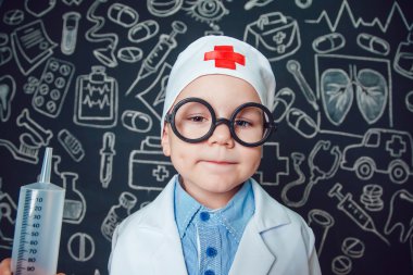 Mutlu küçük çocuk bir doktor desenli koyu arka plan üzerinde şırınga tutarak bardaklarda gibi