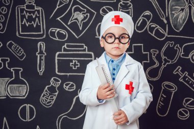 Mutlu küçük çocuk bir doktor desenli koyu arka plan üzerinde şırınga tutarak bardaklarda gibi