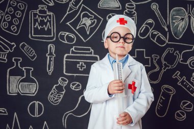Mutlu küçük çocuk bir doktor desenli koyu arka plan üzerinde şırınga tutarak bardaklarda gibi