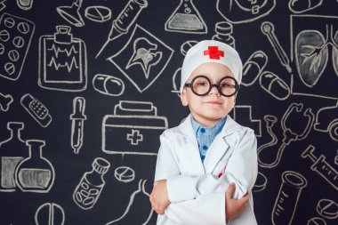 Mutlu küçük çocuk bir doktor gibi ayakta ve katlanmış silah desenli koyu arka plan üzerinde gözlük