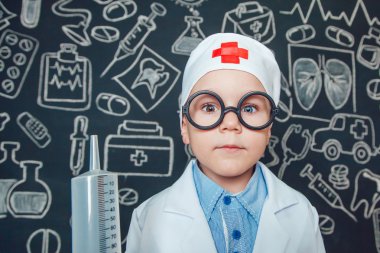Mutlu küçük çocuk bir doktor desenli koyu arka plan üzerinde şırınga tutarak bardaklarda gibi