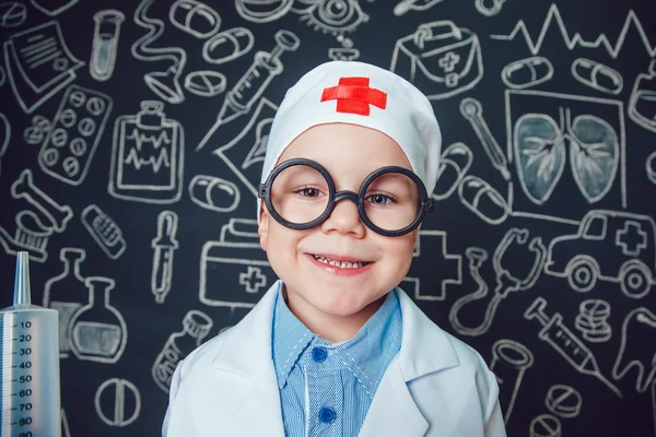 Mutlu küçük çocuk bir doktor desenli koyu arka plan üzerinde şırınga tutarak bardaklarda gibi
